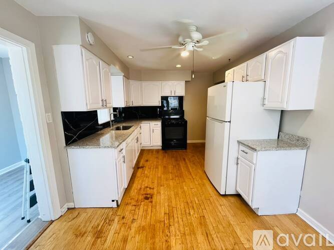 A kitchen with white cabinets and a black countertop.