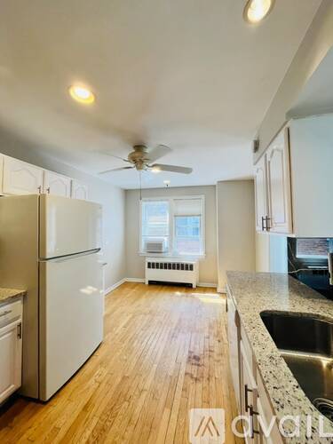A kitchen with a white refrigerator and wooden floors.