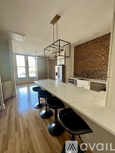 A kitchen with a long white counter and black stools.