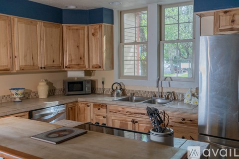 A kitchen with wooden cabinets and a stainless steel refrigerator.