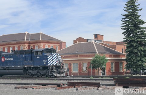 A train with the number 4401 on it is on the tracks in front of a building.