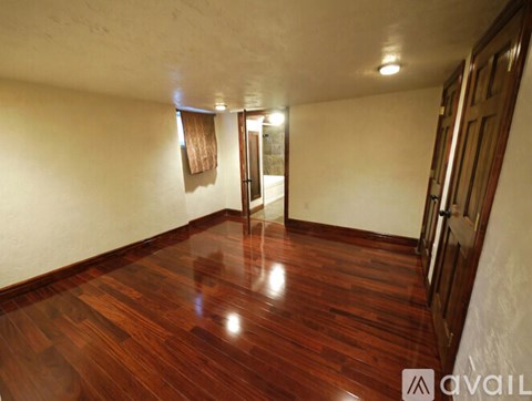 A room with wooden floors and a door on the right side.