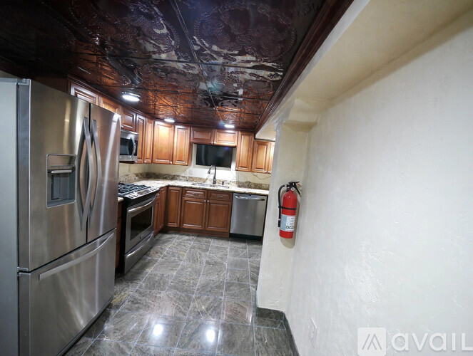 A kitchen with a stainless steel refrigerator and a fire extinguisher on the wall.
