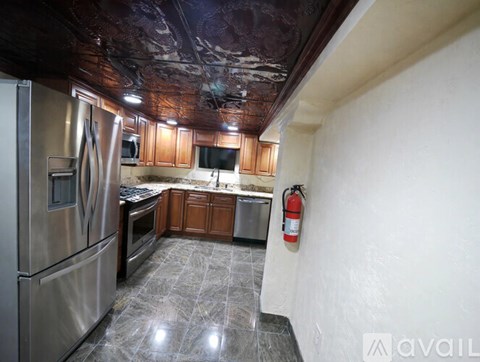 A kitchen with a stainless steel refrigerator and a fire extinguisher on the wall.