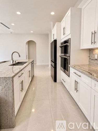 A modern kitchen with white cabinets and a marble countertop.