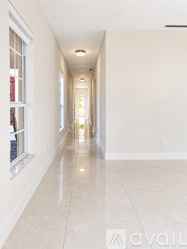 A long hallway with tiled floors and windows on the side.