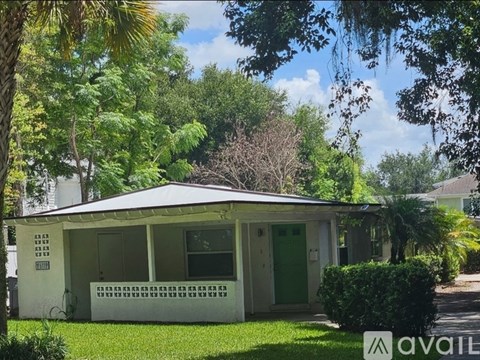 A small white house with a green door and a porch.