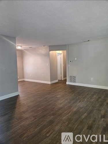 A room with wooden flooring and a doorway leading to another room.