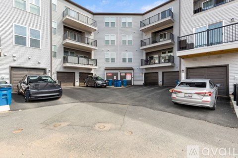 A car is parked in the driveway of a two-story apartment building.