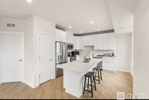 A kitchen with white cabinets and a white island with bar stools.