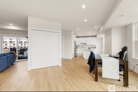 A spacious room with a blue couch, a desk, and a large open door leading to another room.