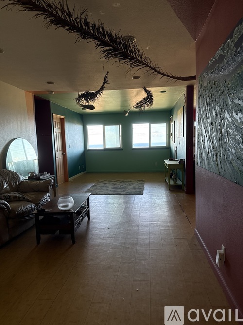 A living room with a couch, a coffee table, and a large feather decoration hanging from the ceiling.