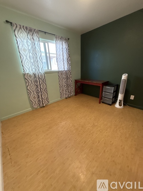 A room with a desk and a window with curtains.
