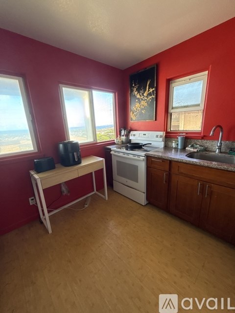 A kitchen with red walls and wooden floors.