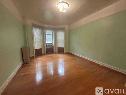 A room with wooden floors and a window with blinds.