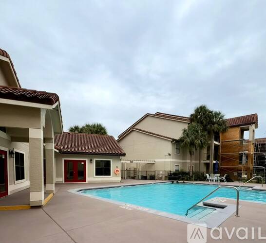 A pool area with a building and a palm tree.