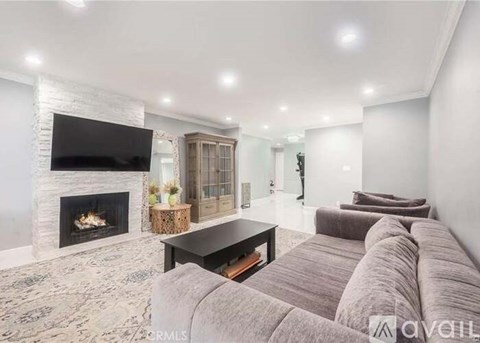 A living room with a grey couch and a fireplace.