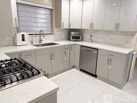 A modern kitchen with a stove, sink, and cabinets.