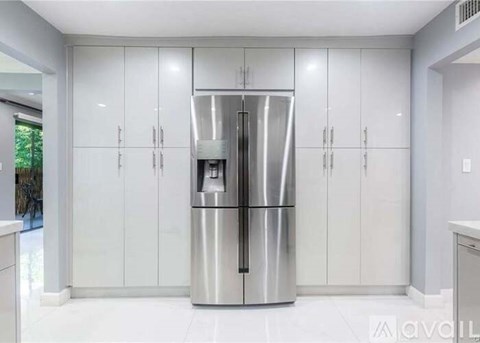 A modern kitchen with a stainless steel refrigerator and white cabinets.