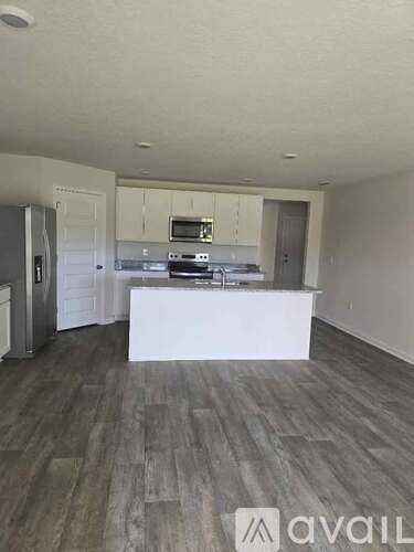 A kitchen with white cabinets and a wooden floor.