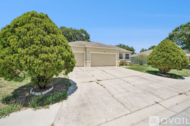 A house with a driveway and two trees.