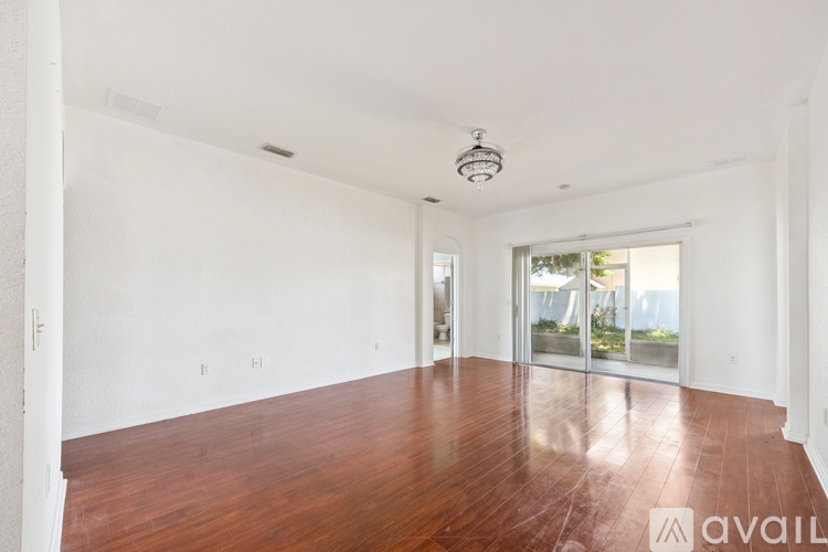 A spacious room with wooden floors and white walls.