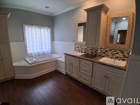 A bathroom with a tub, sink, and mirror.