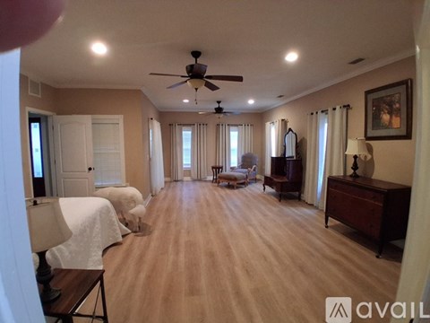 A spacious living room with a ceiling fan and lighting.