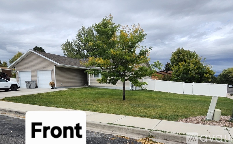 A house with a white fence and a tree in front.
