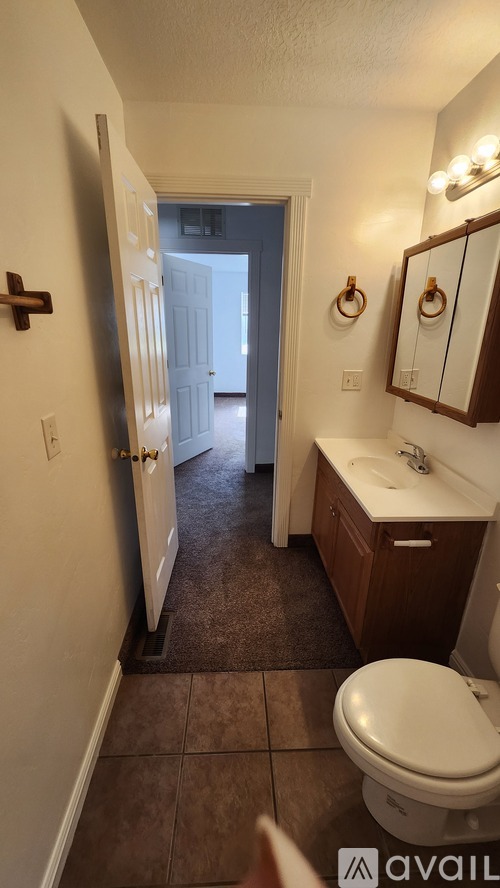 A bathroom with a toilet, sink, and mirror.