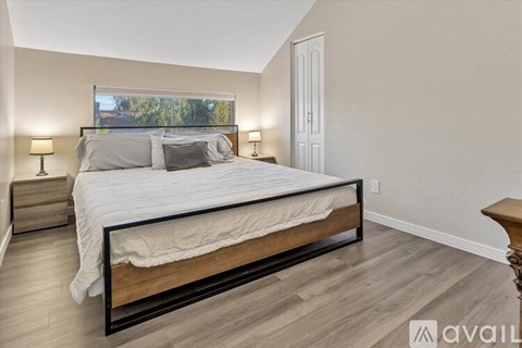 A bedroom with a large bed and a window overlooking trees.