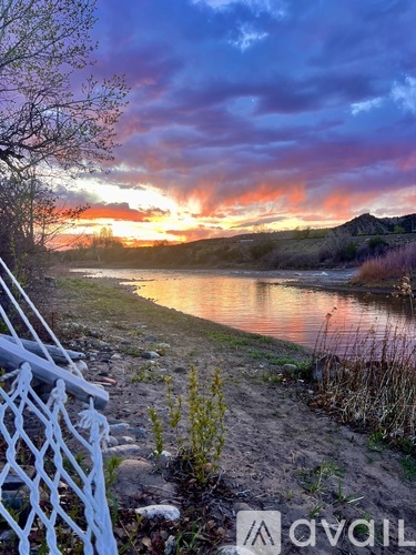 A beautiful sunset over a lake with a white fence in the foreground.