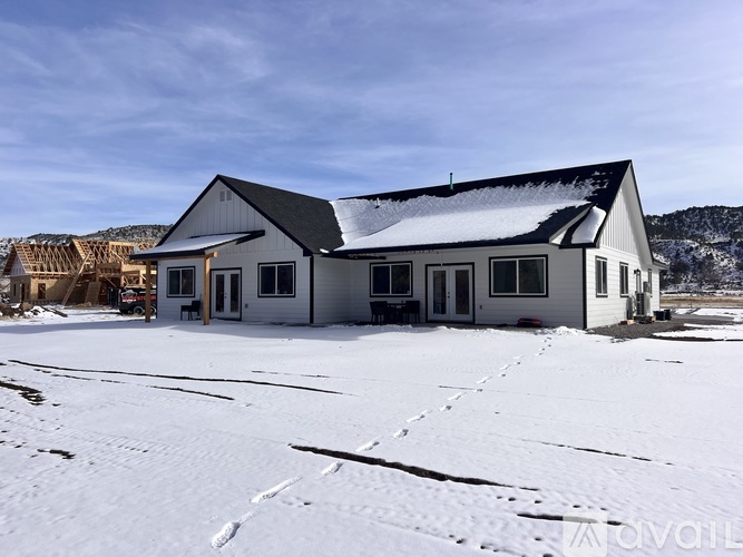A large white building with a black roof is surrounded by snow.