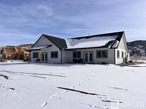A large white building with a black roof is surrounded by snow.