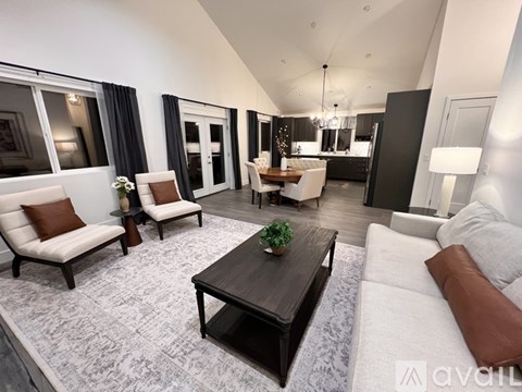 A modern living room with a dark wood coffee table and white furniture.