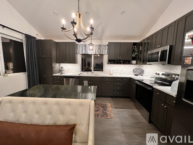 A modern kitchen with dark brown cabinets and a white dining table.