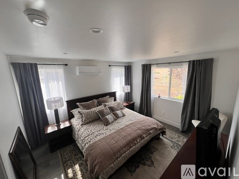 A bedroom with a large bed and a window with curtains.