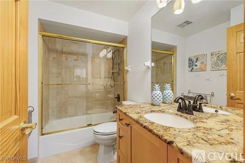 A bathroom with a marble countertop and a walk-in shower.