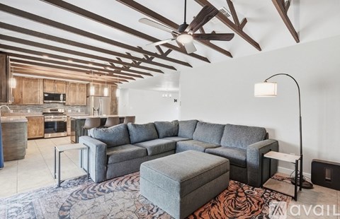 A living room with a grey couch and a wooden ceiling.
