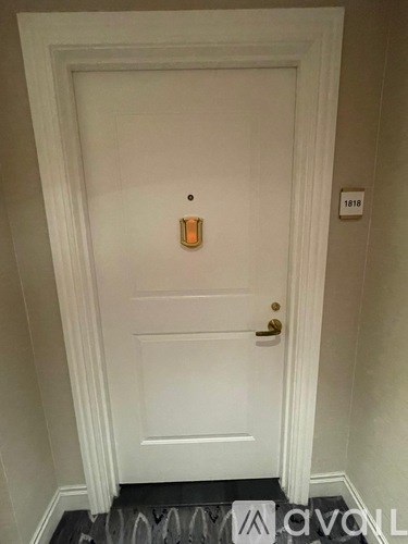 A white door with a gold handle and a number plate on the wall.