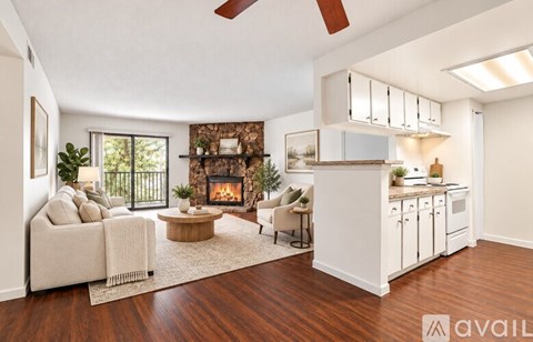 A living room with a fireplace and a kitchen area in the background.