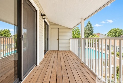 A wooden deck with a sliding glass door leading to a pool.