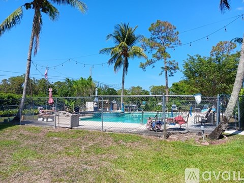 A pool surrounded by palm trees and a fence with a flag on it.