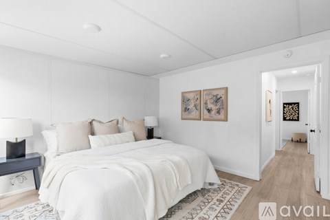 A bedroom with a large bed and a painting on the wall.