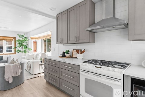 A modern kitchen with a white stove top oven and a grey range hood.