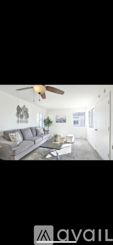 A living room with a grey sofa and a ceiling fan.
