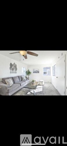 A living room with a grey sofa and a ceiling fan.