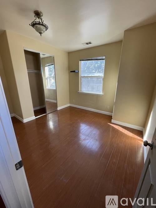 A room with wooden floors and a window with a view of a snowy landscape outside.