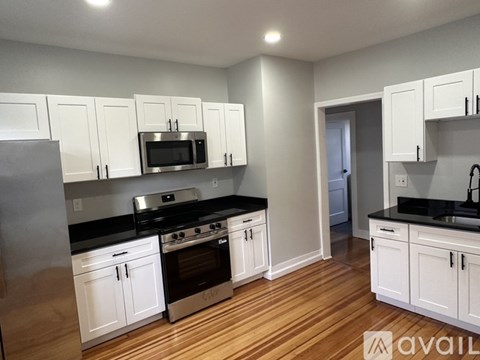 A kitchen with white cabinets and black countertops.