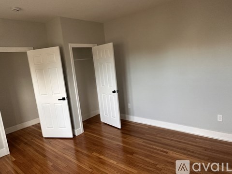 Two white doors in a room with wooden floors.